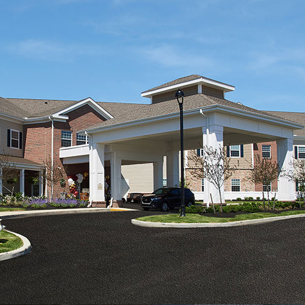 square photo of the front of the grove city senior living building showing entrance and car port