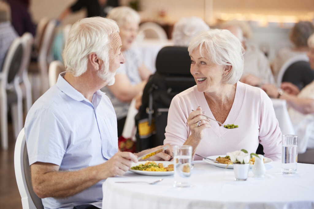 A senior man and senior woman sitting together at a dining table smiling