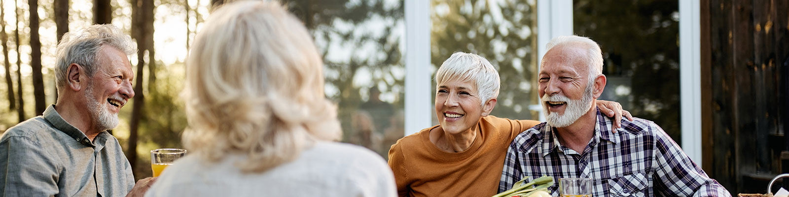 four people sitting around a table outside of a senior villa home in the fall